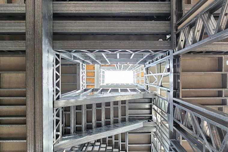 Caixa de escadas em light steel frame vista de baixo, com os perfis metálicos
              dos vários pisos alinhados.