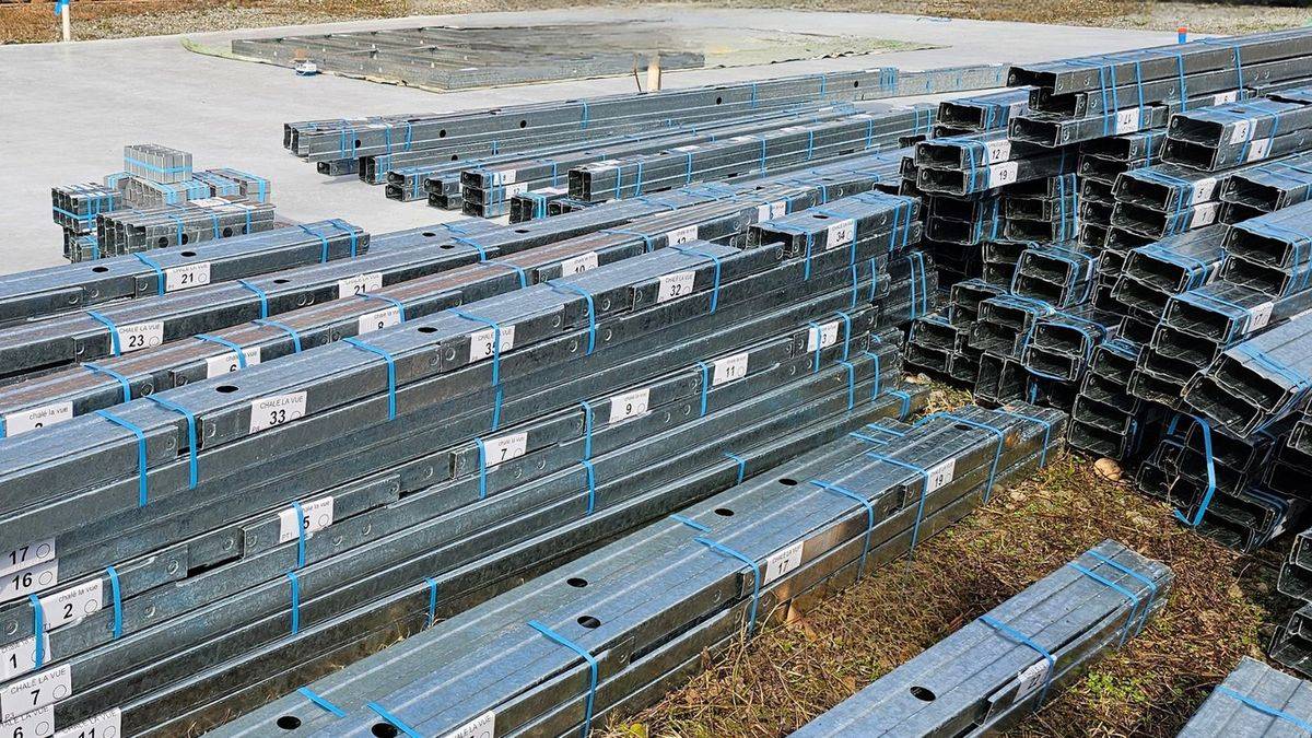 Perfis de aço galvanizado em light steel frame empilhados em paletes, no
              estaleiro, prontos para montagem.