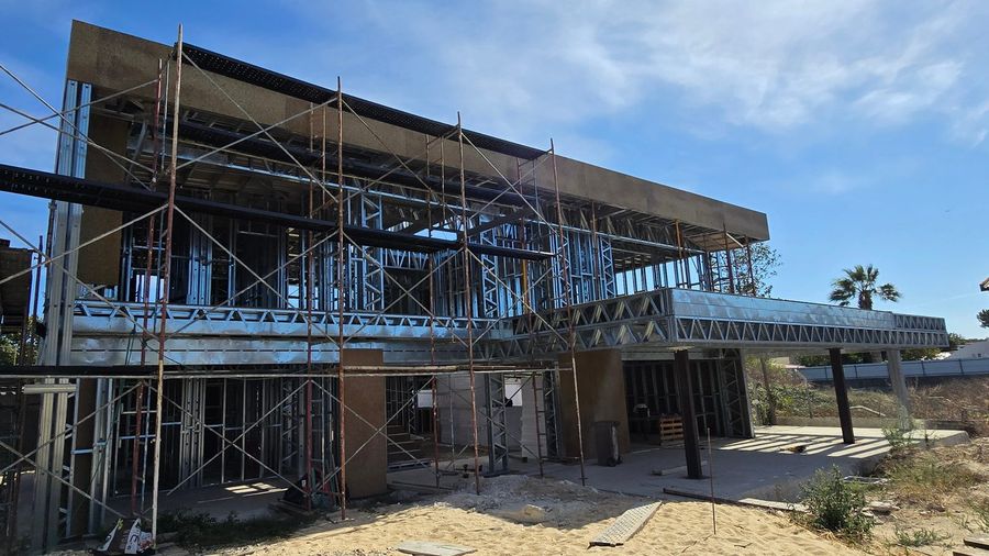 Moradia Oliveira em construção: estrutura em perfis de aço galvanizado montada
                  sobre a laje, com andaimes e paredes já revestidas a OSB.